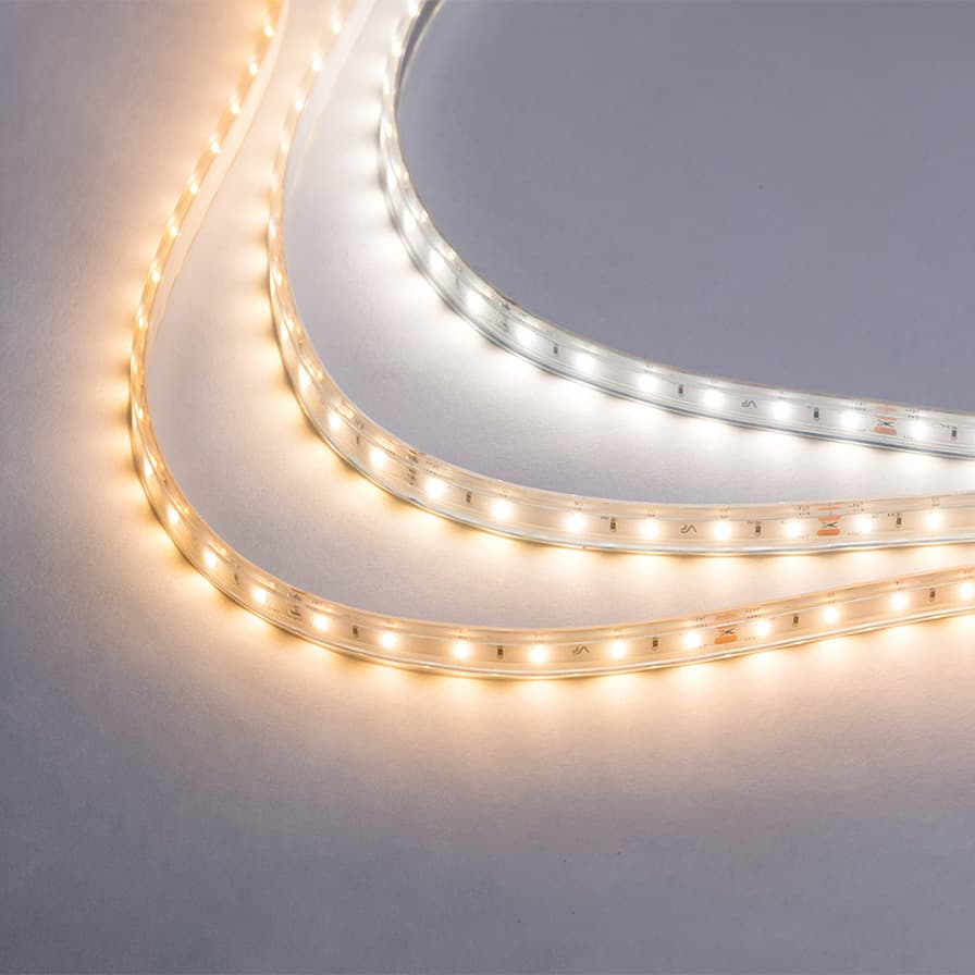 Flexible LED strip lit in three colour temperatures, coiled on a grey background.